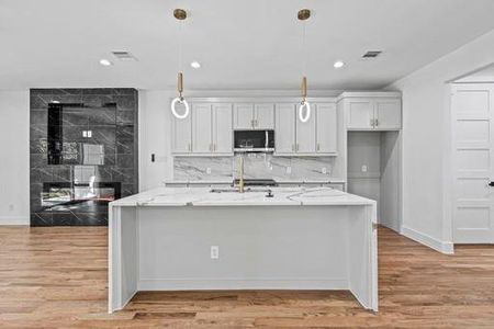 Kitchen featuring light stone countertops, light hardwood / wood-style flooring, and hanging light fixtures