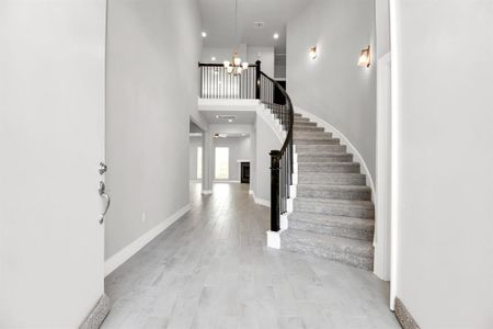 The majestic entryway allures with its high ceilings, embellished withsophisticated wood-look tile flooring and sleek oversized baseboards. Lift youreyes to a captivating sight of the open staircase, and follow the trail of naturallight pouring in through expansive windows as you journey to the family room,crafting an inviting and cozy ambiance. Sample photo of completed home with similar floor plan. Actual colors and selections may vary.