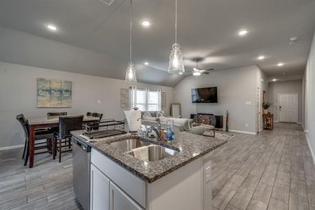 Kitchen featuring lofted ceiling, a center island with sink, white cabinetry, light hardwood / wood-style flooring, and sink