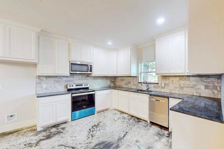 Kitchen with white cabinets, appliances with stainless steel finishes, and sink