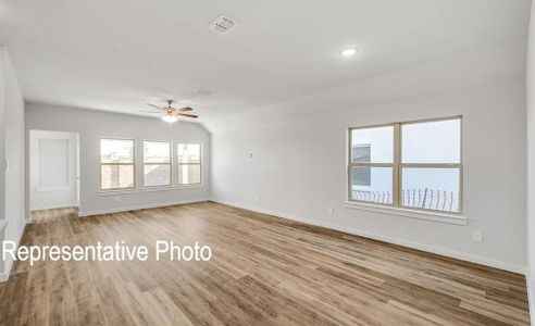 Empty room featuring ceiling fan, light wood-type flooring, and lofted ceiling