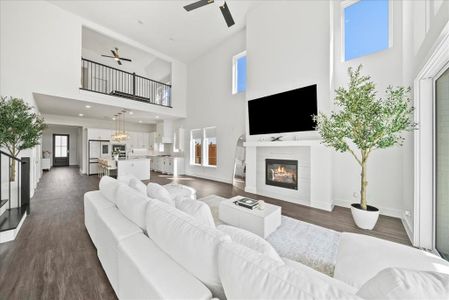 Living room with dark wood-style floors, a tile fireplace, a ceiling fan, and baseboards