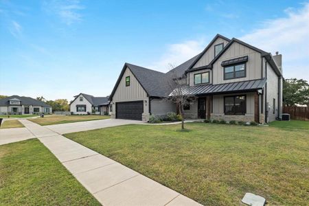 Modern inspired farmhouse with a front lawn, central air condition unit, and a garage