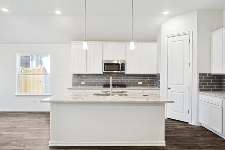 Kitchen with a kitchen island with sink, white cabinets, and dark hardwood / wood-style floors