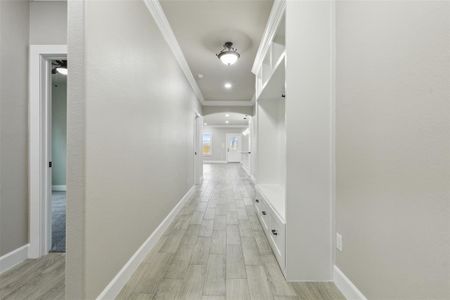 Hallway with crown molding and light wood-type flooring