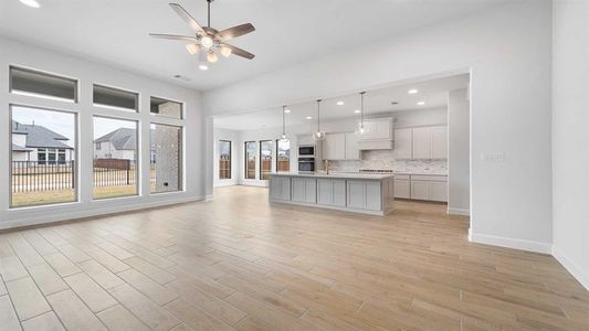 Kitchen with a center island with sink, ceiling fan, decorative backsplash, built in microwave, and decorative light fixtures