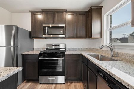 Kitchen featuring sink, light stone counters, light wood-type flooring, and stainless steel appliances