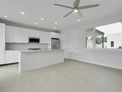 The spacious living room features a ceiling fan and seamlessly transitions into the kitchen, where culinary dreams come to life.