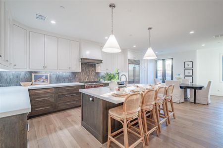 Kitchen with Sub Zero fridge, Wolf range stove, marble backsplash, 2 inch thick quartz countertops, and an island with sink.