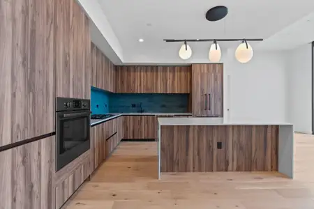 The modern kitchen features elegant terrazzo style quartz countertops with a pop of color adding to the sophisticated Midcentury Austin aesthetic.