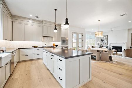 The kitchen features custom built soft close shaker cabinets and drawers with black hardware, quartz counters, an apron front porcelain farmhouse sink and a large island with storage & seating.