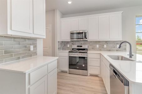 Kitchen with white cabinetry, sink, and appliances with stainless steel finishes