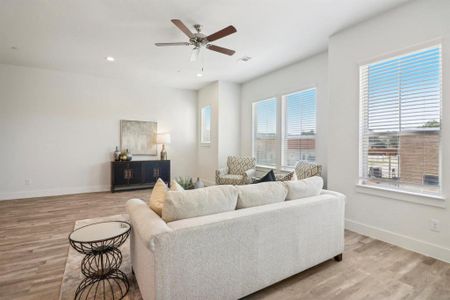 Living room featuring a wealth of natural light, ceiling fan, and light wood-type flooring