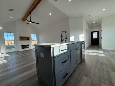 Kitchen with beam ceiling, ceiling fan, dark hardwood / wood-style flooring, stainless steel dishwasher, and a kitchen island with sink