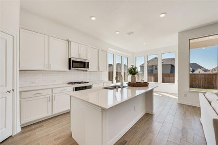 Kitchen featuring white cabinetry, gas stovetop, light hardwood / wood-style flooring, a kitchen island with sink, and sink