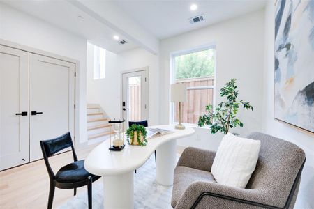 Living area with beamed ceiling and light wood-type flooring