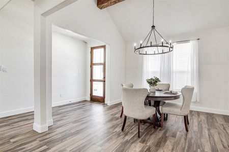 Dining area featuring beam ceiling, dark hardwood / wood-style floors, high vaulted ceiling, and a notable chandelier