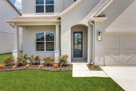 View of exterior entry with a garage and a lawn