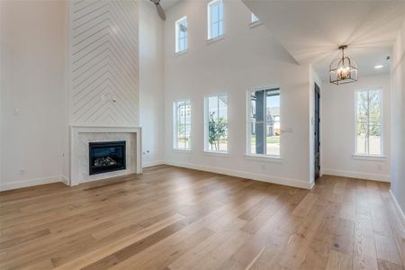 Unfurnished living room with light wood-type flooring, a premium fireplace, and a healthy amount of sunlight