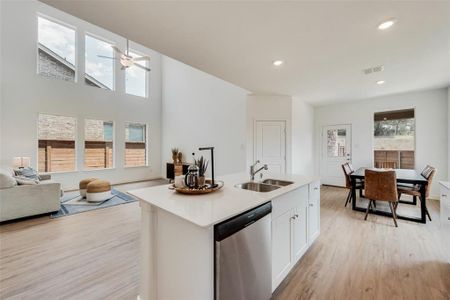 Kitchen with white cabinetry, a kitchen island with sink, stainless steel dishwasher, light wood-type flooring, and sink