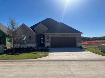 View of beautiful brick and stone front facade just completed October 16, 2024 with a front yard that is always mowed and landscaped by your HOA and an oversized 2 car garage.