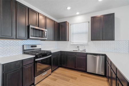 This spacious kitchen features large windows, high ceilings, stained wood cabinets, silestone countertops, SS appliances, modern tile backsplash, recessed lighting, and pantry all overlooking your huge family room.