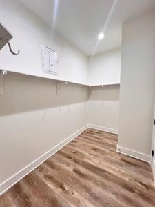 A spacious, empty walk-in closet featuring polished wood floors and ample room for storage and organization.