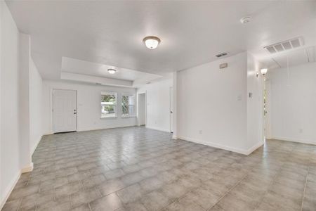 Unfurnished living room with a raised ceiling and light tile patterned floors