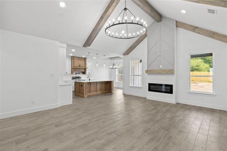 Unfurnished living room featuring light hardwood / wood-style flooring, beam ceiling, and a chandelier