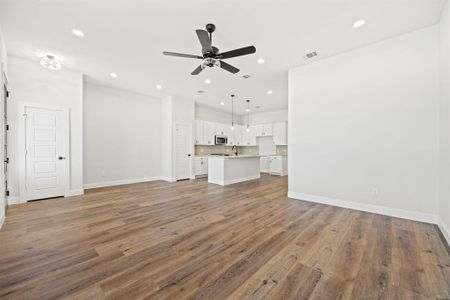 Unfurnished living room featuring hardwood / wood-style flooring, ceiling fan, and sink