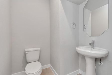 Immerse yourself in modern elegance within this delightful half bathroom. Featuring a sophisticated 5-panel door, upgraded pedestal sink, contemporary hardware, and stylish vanity lights, it exudes a sense of refinement. Sample photo of completed home with similar floor plan. As-built interior colors and selections may vary.