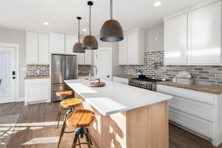 Kitchen with white cabinetry, dark wood-type flooring, an island with sink, and stainless steel appliances