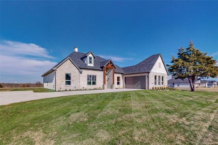 View of front of property featuring a front lawn and a garage