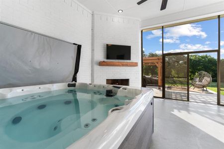 Misc room featuring ceiling fan, a hot tub, and a brick fireplace