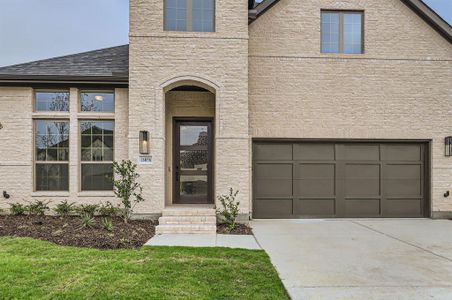 Entrance to property featuring a garage and a lawn