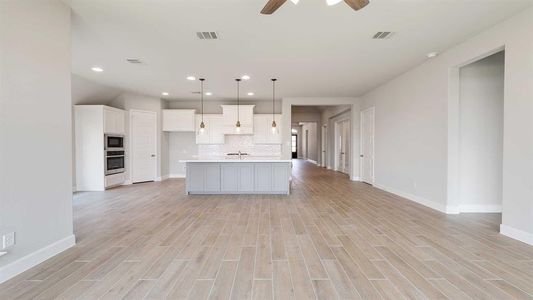 Kitchen featuring pendant lighting, light hardwood / wood-style floors, decorative backsplash, an island with sink, and ceiling fan