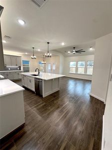 Kitchen with dishwasher, backsplash, dark hardwood / wood-style floors, an island with sink, and decorative light fixtures