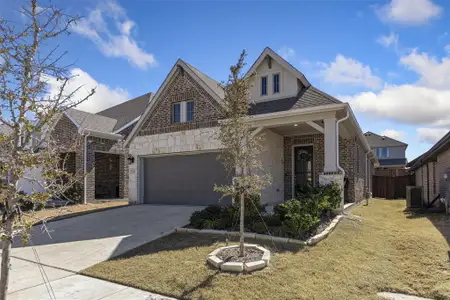 View of front facade with an attached garage, brick siding, a shingled roof, driveway, and stone siding