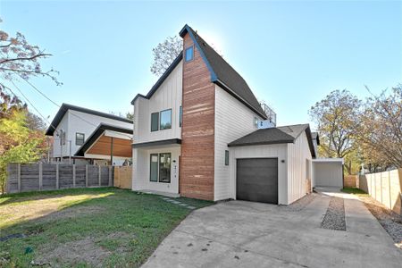 Rear view of house featuring a garage and a yard