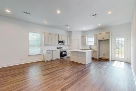 Kitchen featuring wood-type flooring, sink, a center island, and electric range oven