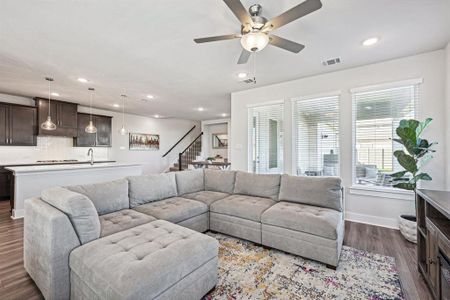 Living room with ceiling fan, light LVP flooring, picture windows