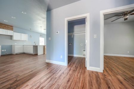 Unfurnished living room with sink, ceiling fan, and wood-type flooring