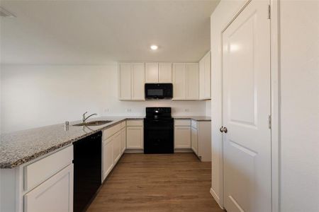 Kitchen featuring light stone counters, white cabinets, sink, black appliances, and dark hardwood / wood-style floors