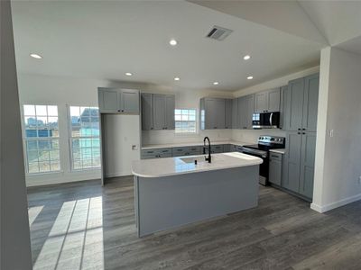 Kitchen featuring gray cabinetry, sink, dark hardwood / wood-style floors, a kitchen island with sink, and appliances with stainless steel finishes