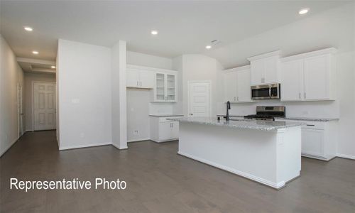 Kitchen with appliances with stainless steel finishes, an island with sink, and white cabinets