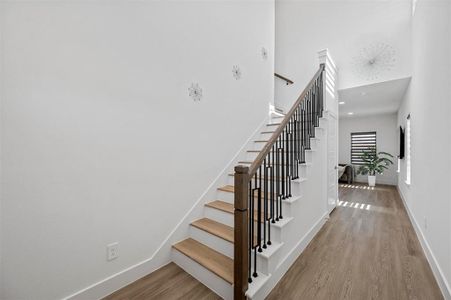 Staircase featuring wood finished floors, a towering ceiling, and baseboards