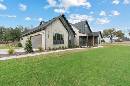 Modern inspired farmhouse featuring a front yard, central AC unit, and a garage