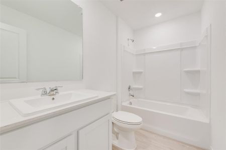 Full bathroom with hardwood / wood-style flooring, toilet, vanity, and shower / washtub combination