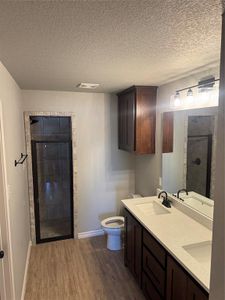 Bathroom with vanity, a shower, a textured ceiling, and wood-type flooring