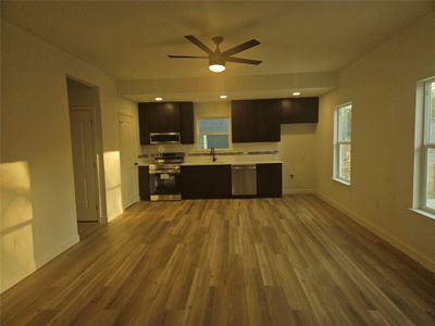 Kitchen featuring ceiling fan, baseboards, light countertops, wood finished floors, and stainless steel appliances